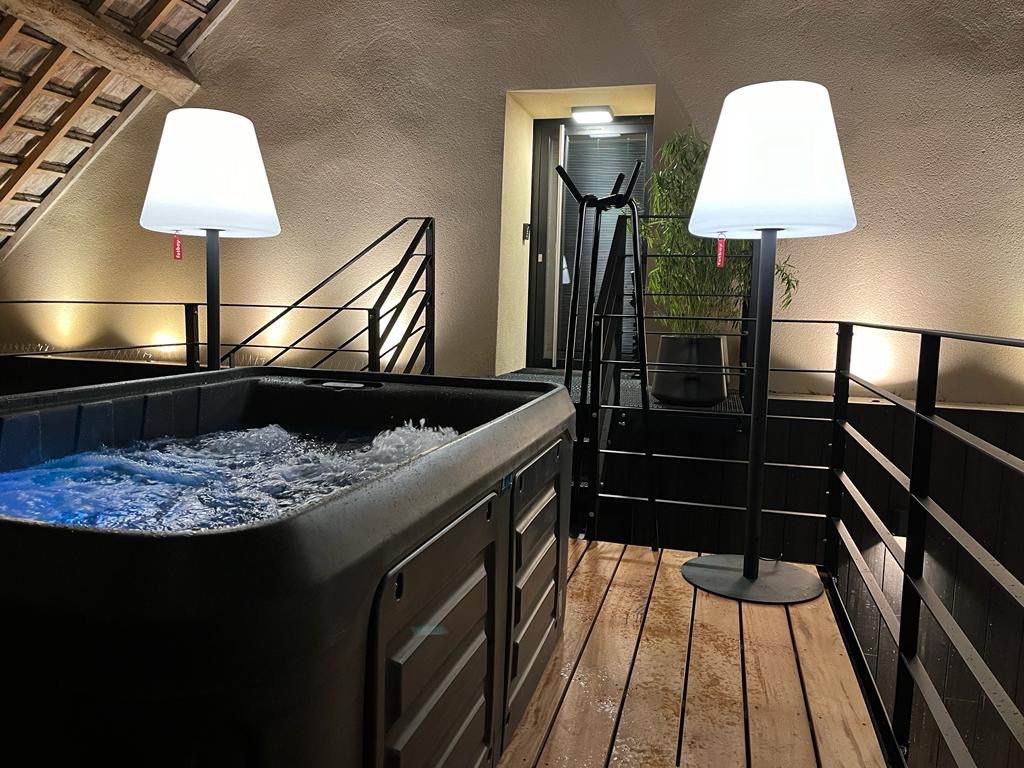 Spa extérieur anthracite en fonctionnement sur une terrasse aménagée et éclairée