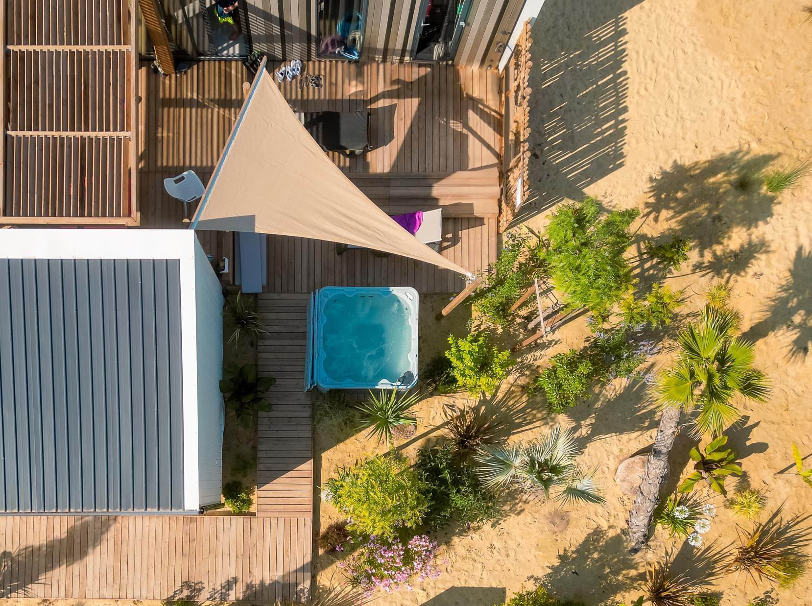 Vue a&eacute;rienne d'un spa install&eacute; pr&egrave;s d'un h&eacute;bergement et d'une terrasse ombrag&eacute;e
